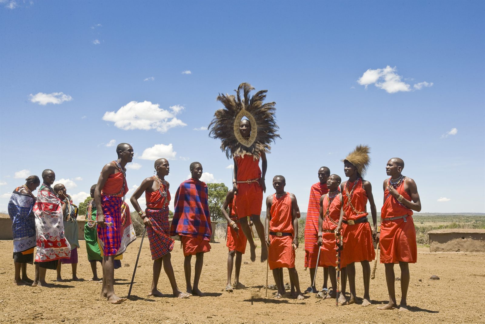 Maasai men in red shukas and a beaded headdress dancing on open grassland, an experience travel advisor fam trips can include