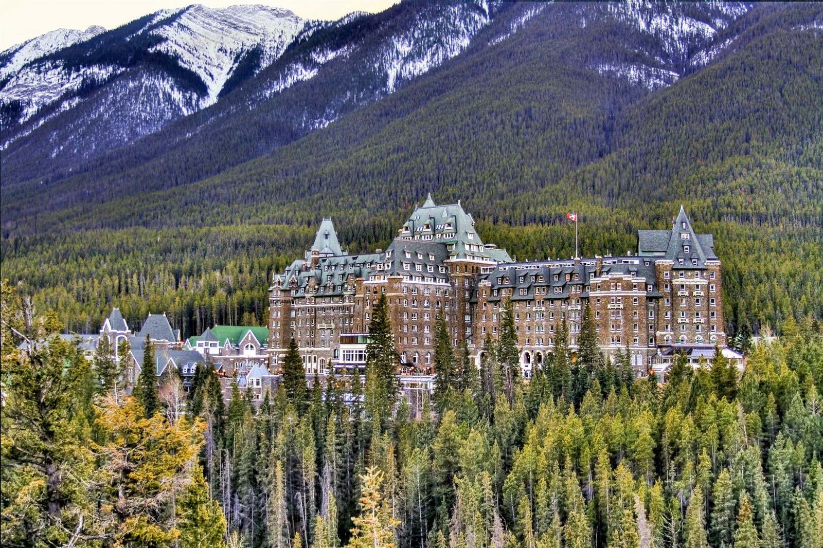 Castle-style grand hotel among pine forest below snowy mountains in Banff, Canada, the kind of hotel offering travel agent hotel rates